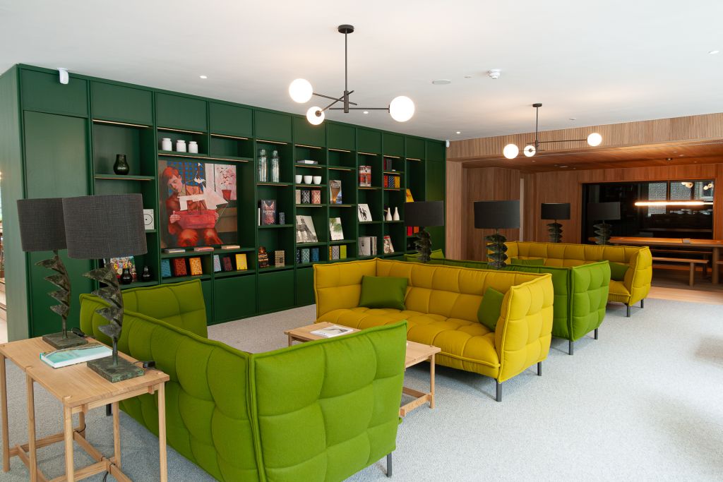 floor to ceiling green shelving units with green high backed sofas
