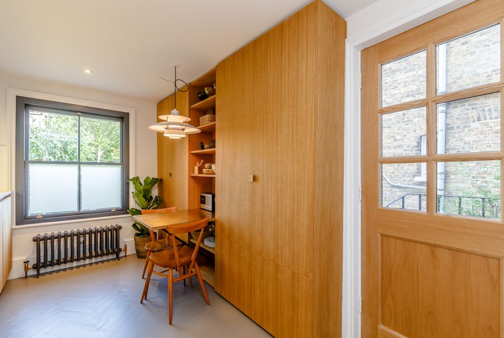 floor to ceiling oak capboards with central open shelves and a brass topped cantilever table